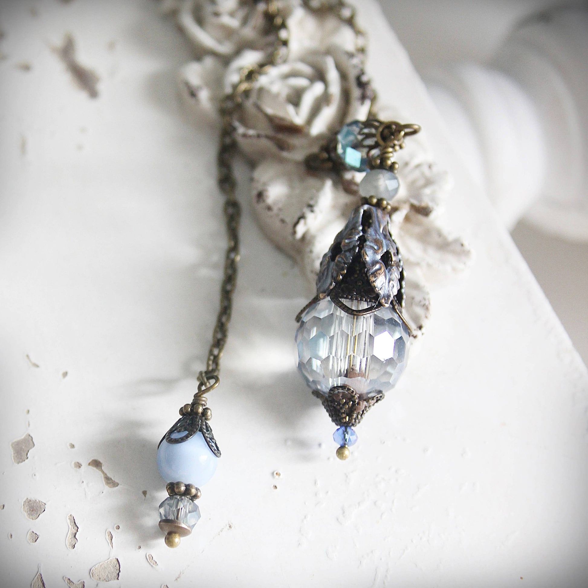 Delicate necklace with crystal pendant and beads on a textured white surface