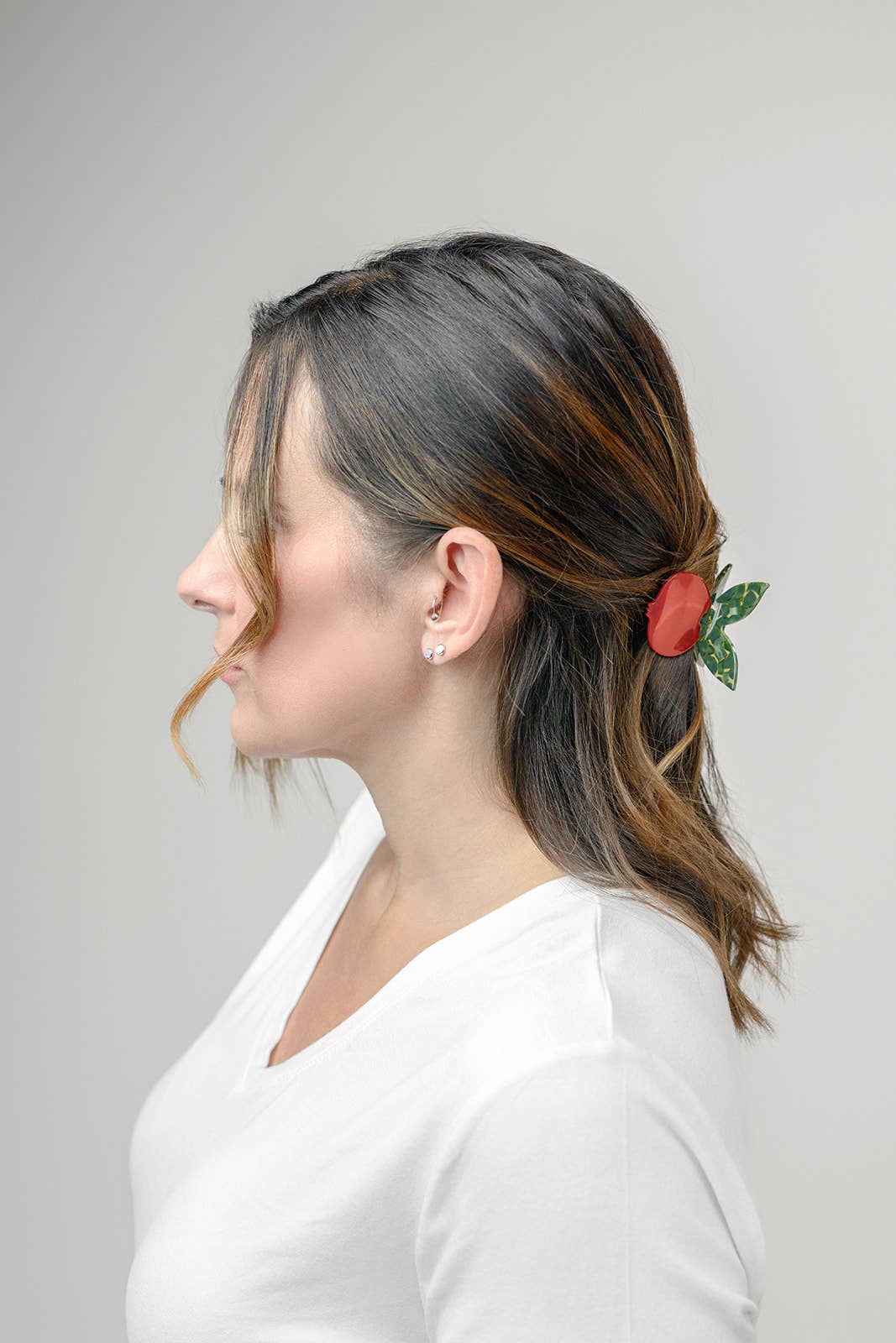 Woman with a side ponytail with a decorative flower against a plain background