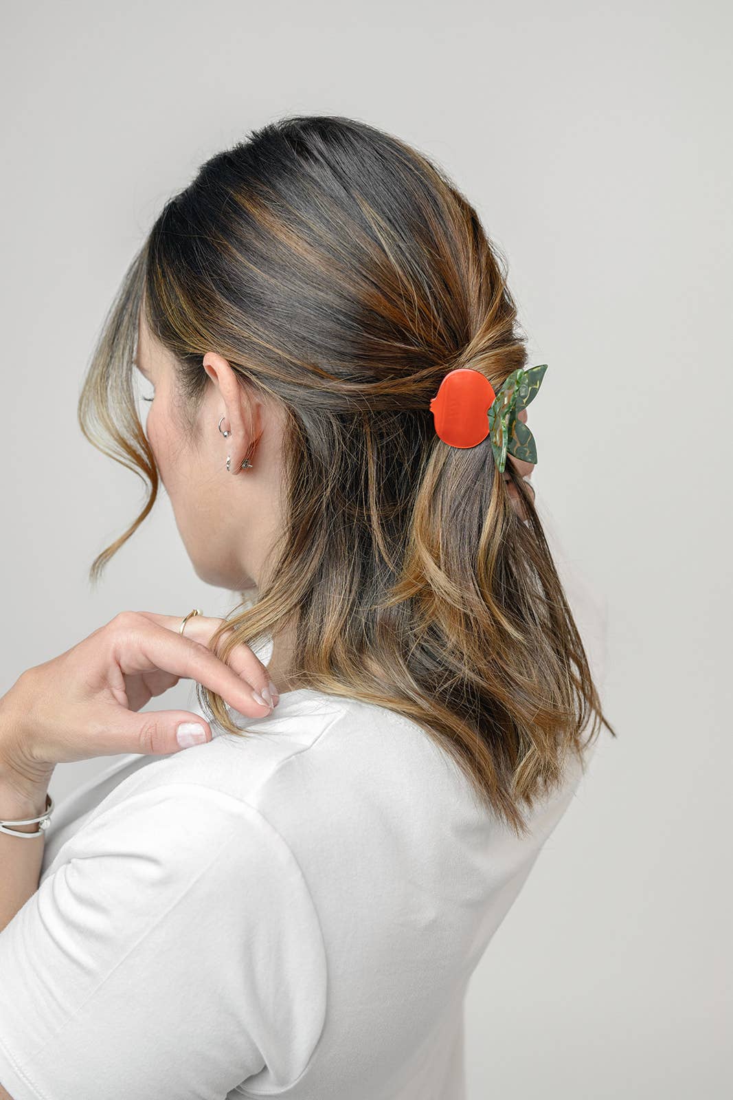 Person with hair tied back using a red hair tie against a plain background