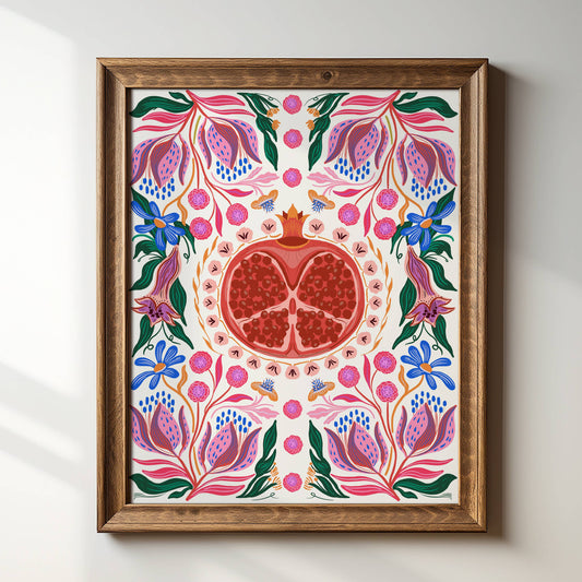 Pomegranate art print in wood frame on a white wall.