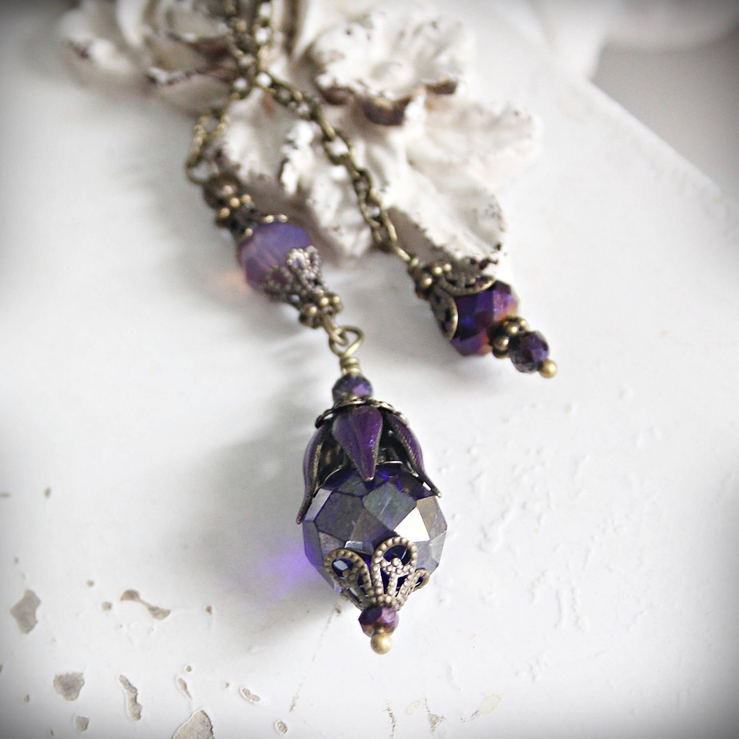 Purple beaded pendulum with gold accents on a textured white surface