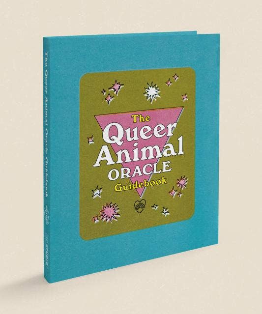 Book titled 'The Queer Animal Oracle Guidebook' with a teal cover on a beige background