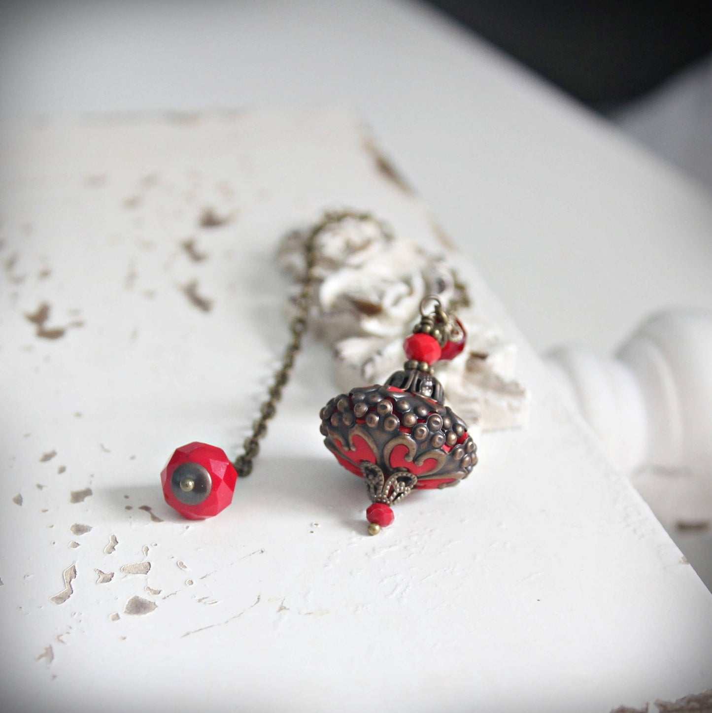 Pendulum with red and silver pendants on a textured white surface