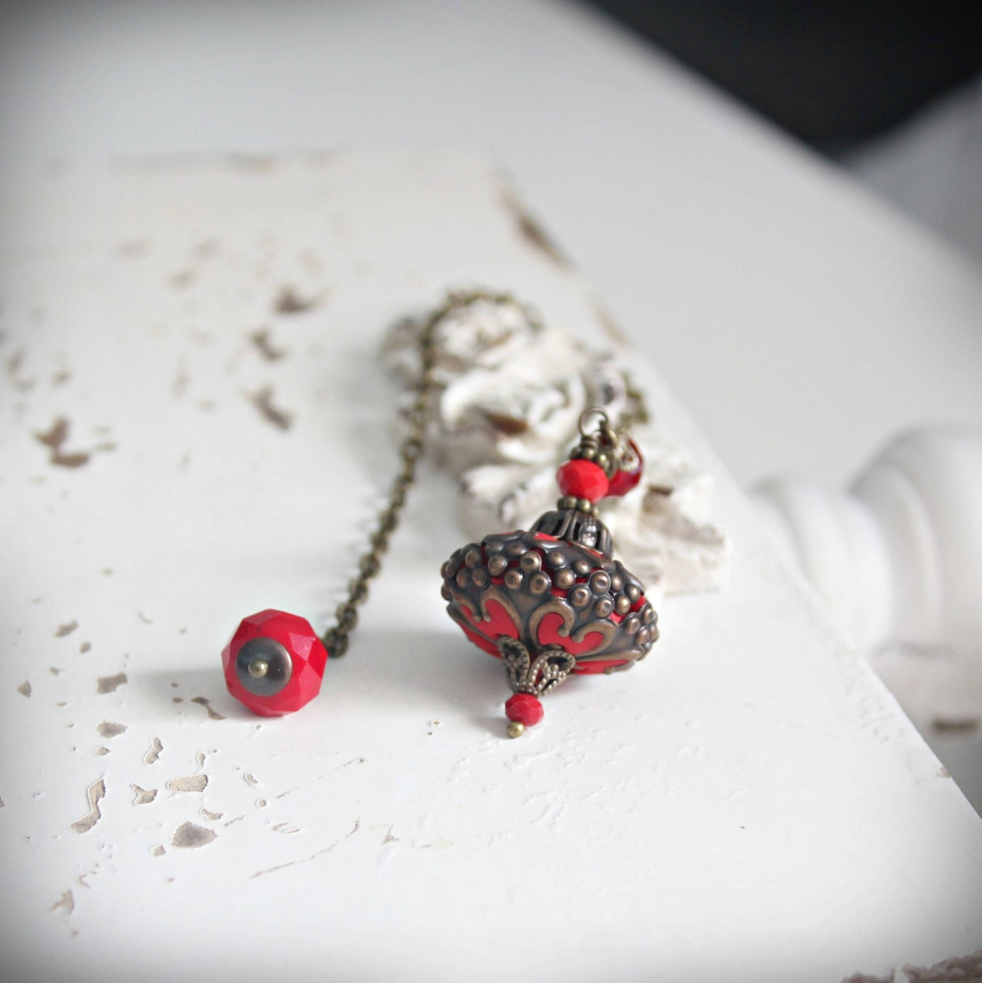 Pendulum with red and silver pendants on a textured white surface