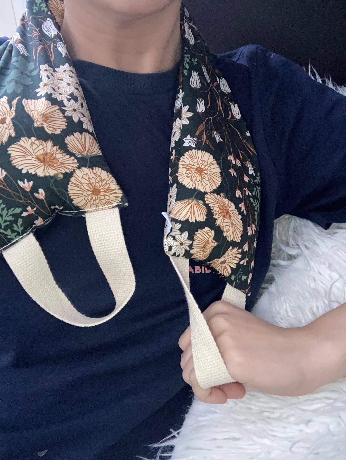 Person wearing a floral-patterned garment with a strap over their shoulder.