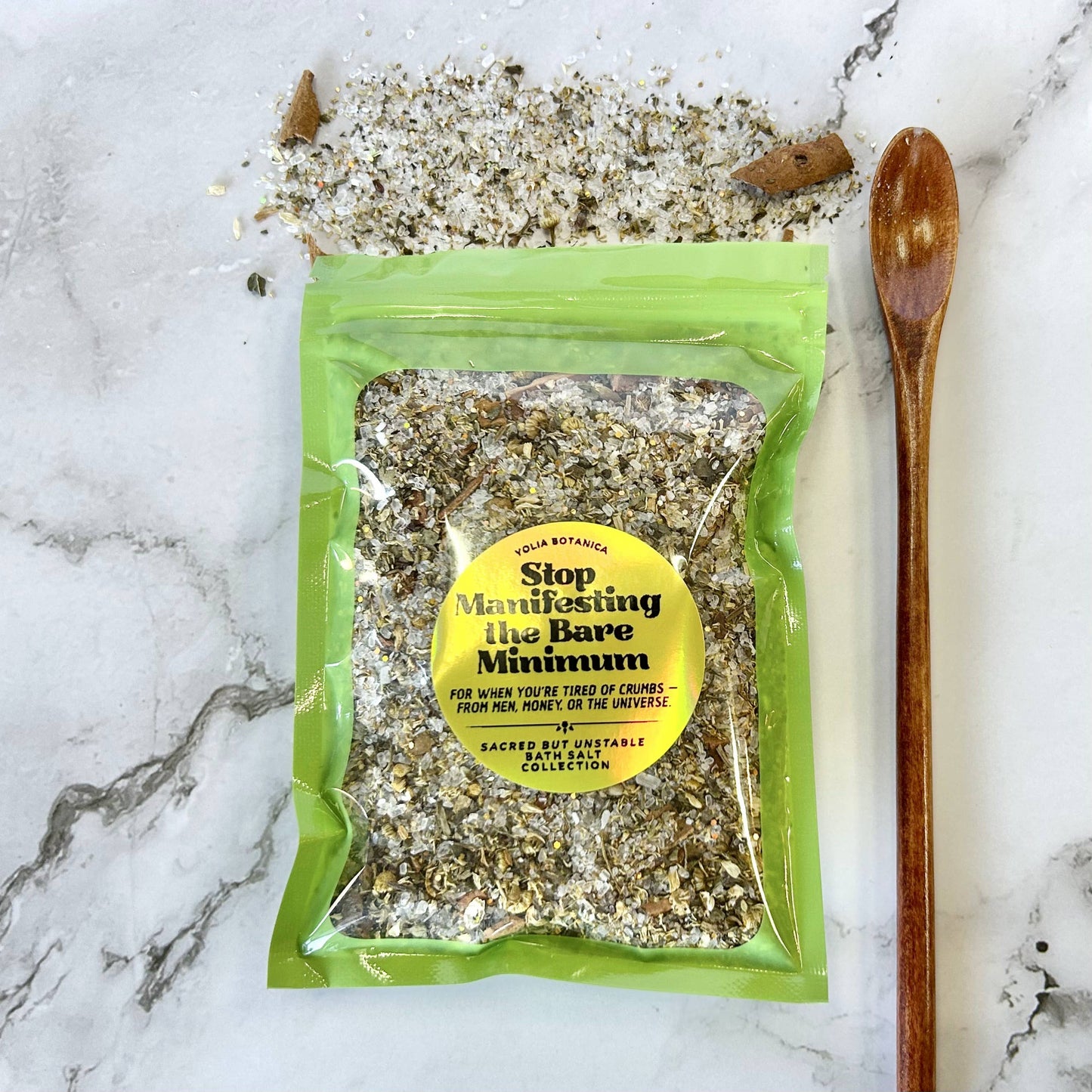 Packaged product with a yellow label on a marble surface with a wooden spoon.