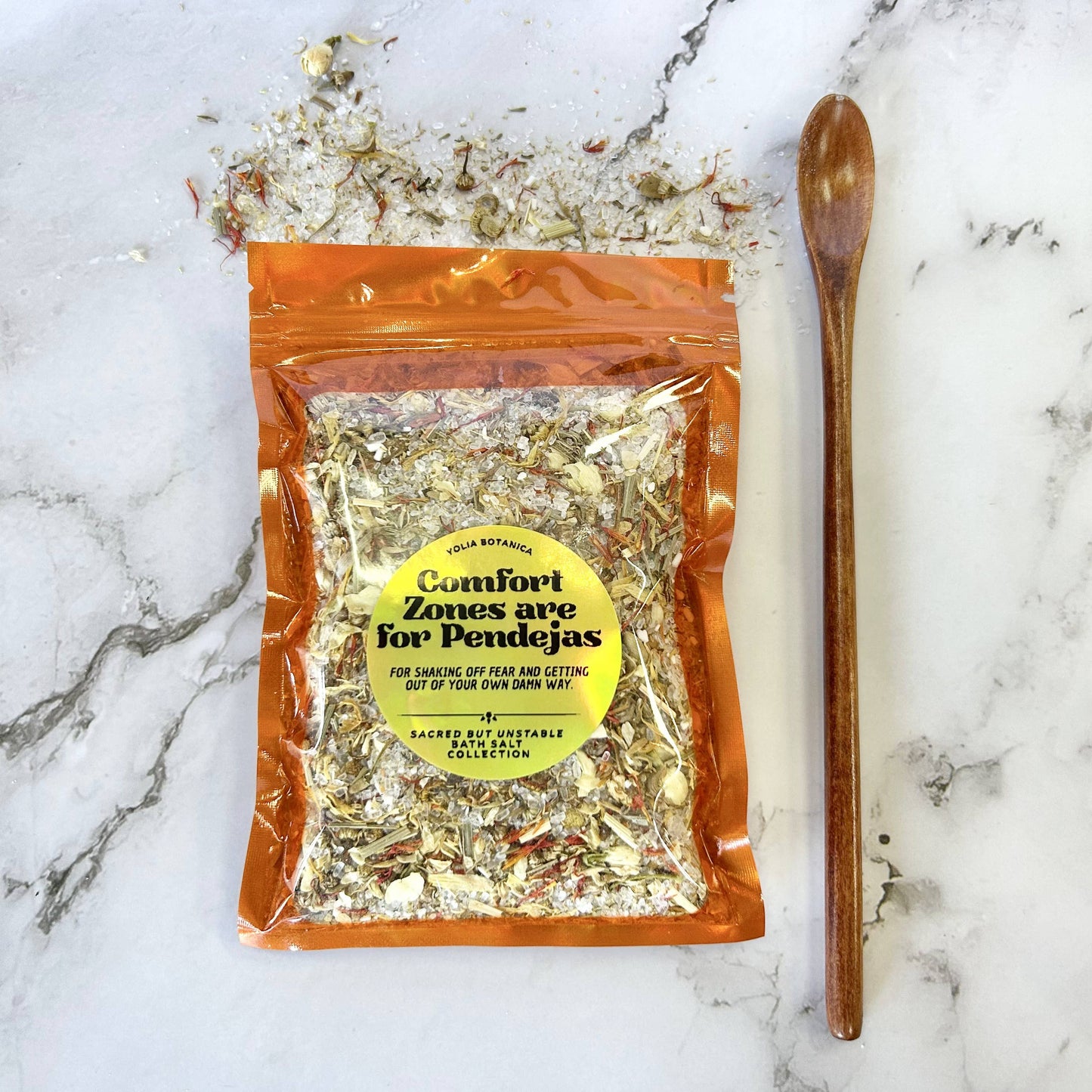 Packaged herbal mix with a wooden spoon on a marble surface