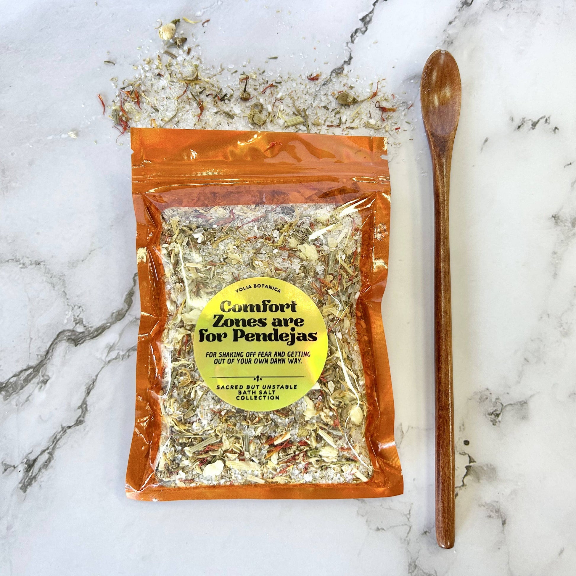 Packaged herbal mix with a wooden spoon on a marble surface