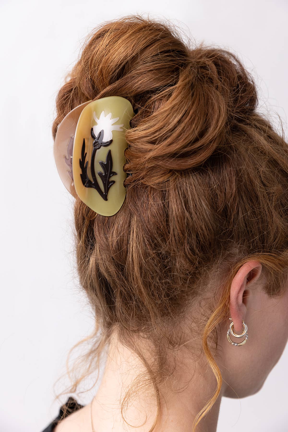 Woman with a hair clip in her bun against a white background