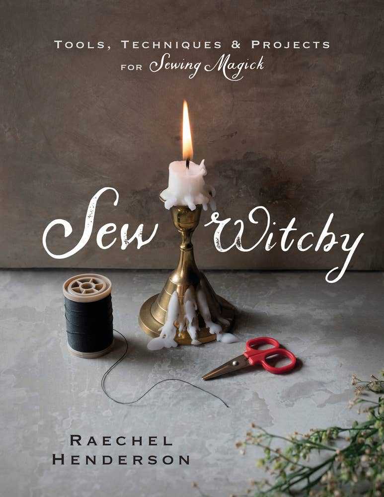 Book cover for 'Sew Witchy: Tools, Techniques & Projects for Sewing Magick' by Raechel Henderson, featuring a lit white candle in a brass holder, a spool of black thread, and red-handled scissors on a textured gray surface.