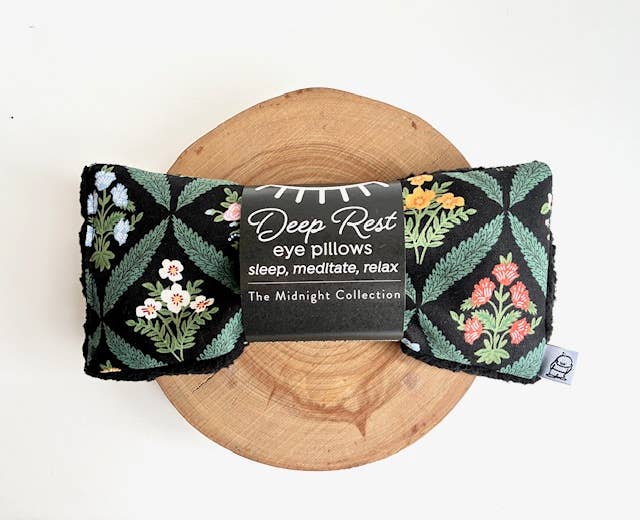 Floral eye pillow on a wooden board with a label indicating it's part of the 'Deep Rest' collection.