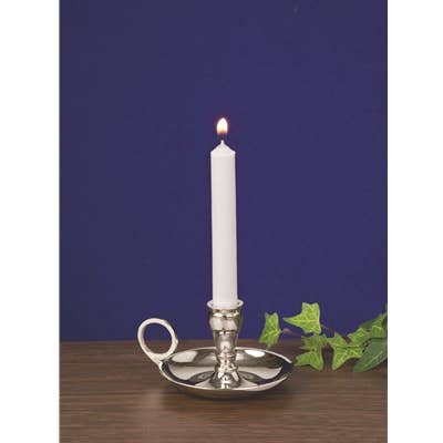 Silver candle holder with a lit white candle on a wooden surface and dark blue background