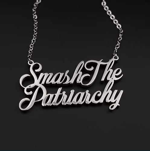 Close up of a silver necklace that says "Smash the Patriarchy ".