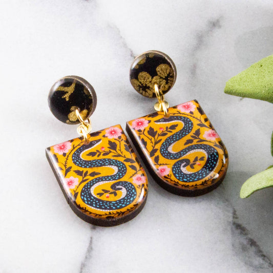Decorative earrings with snake design on a marble surface
