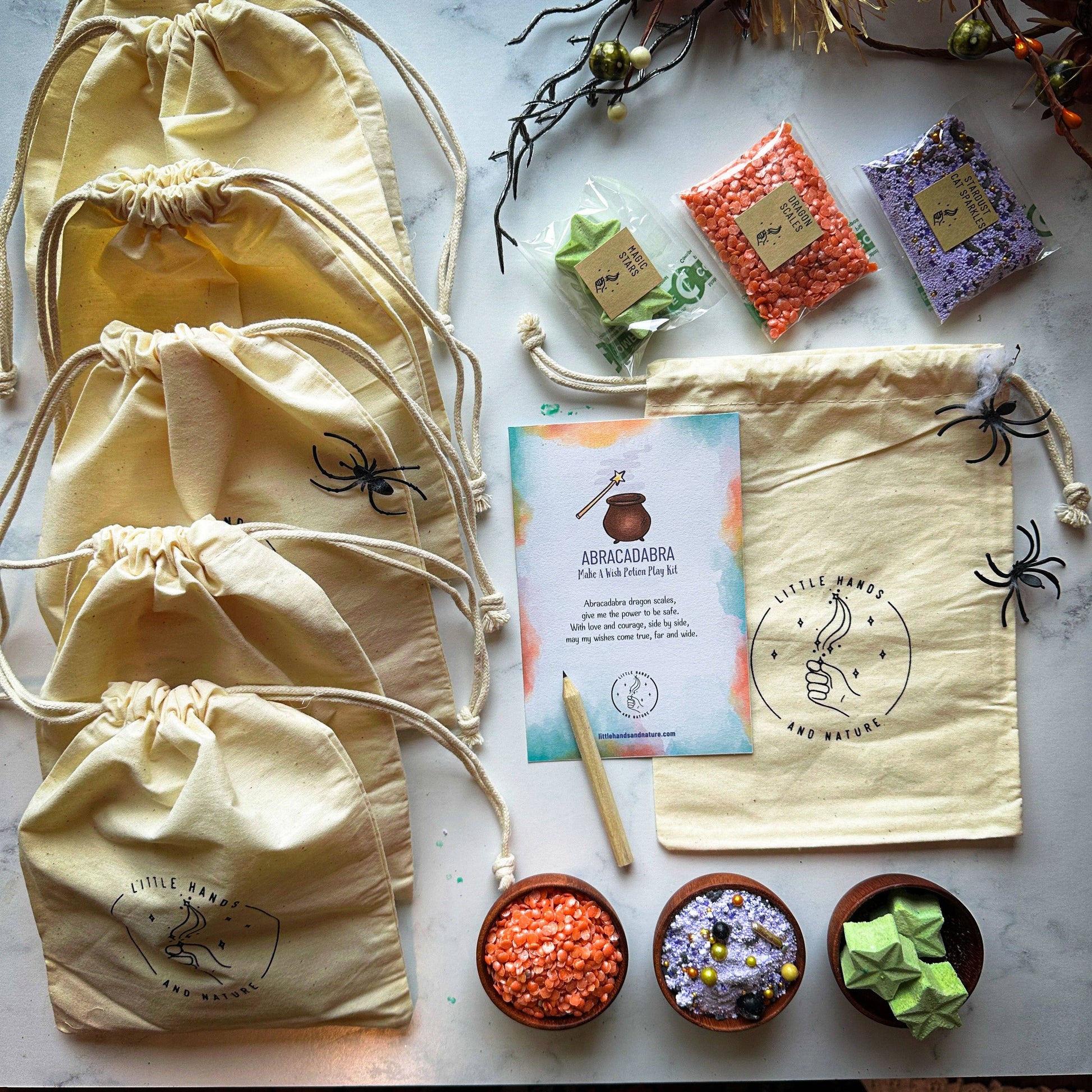 Halloween-themed items including drawstring bags, colored sands, and a card on a marble surface.
