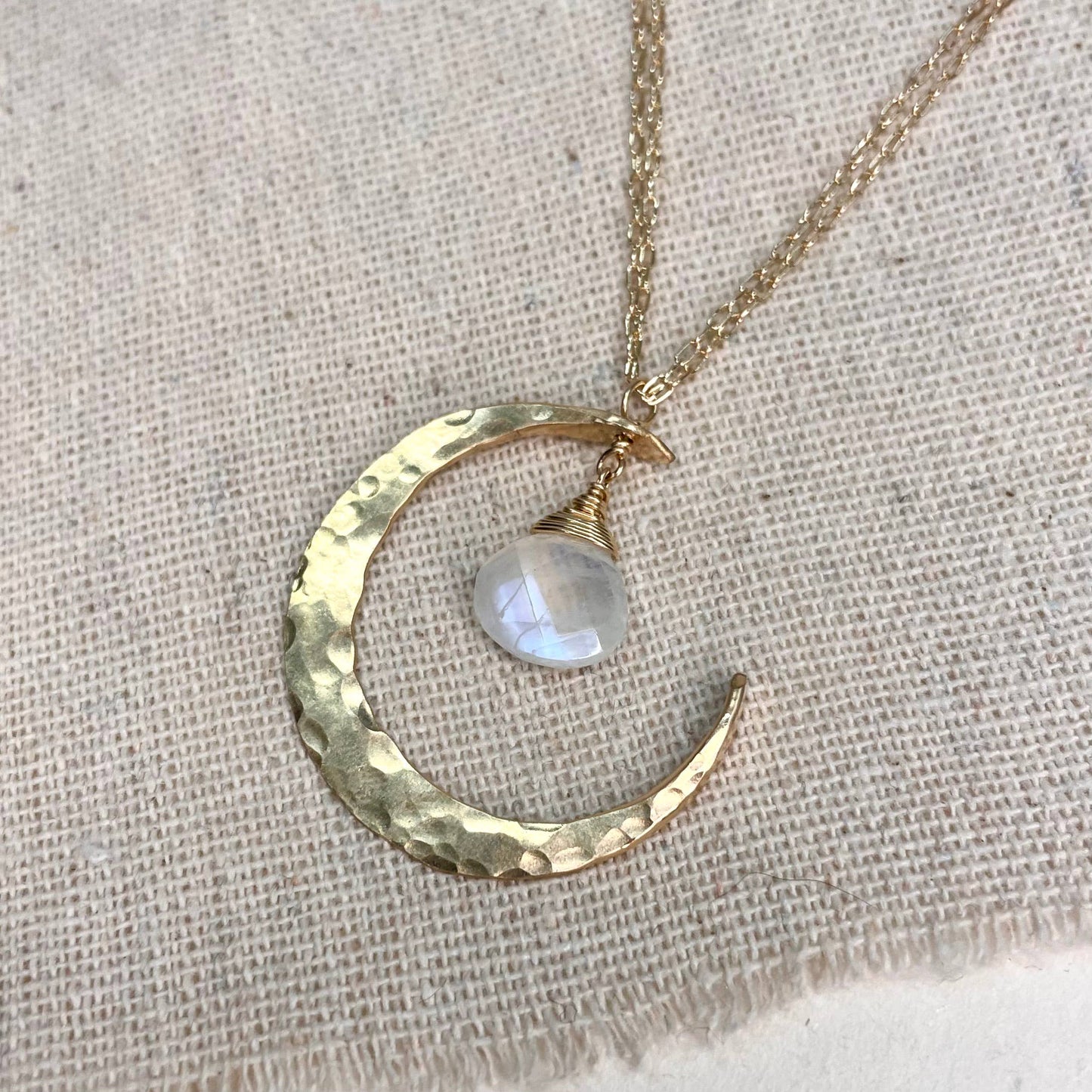 Sterling silver and moonstone crescent moon necklace on a light background.