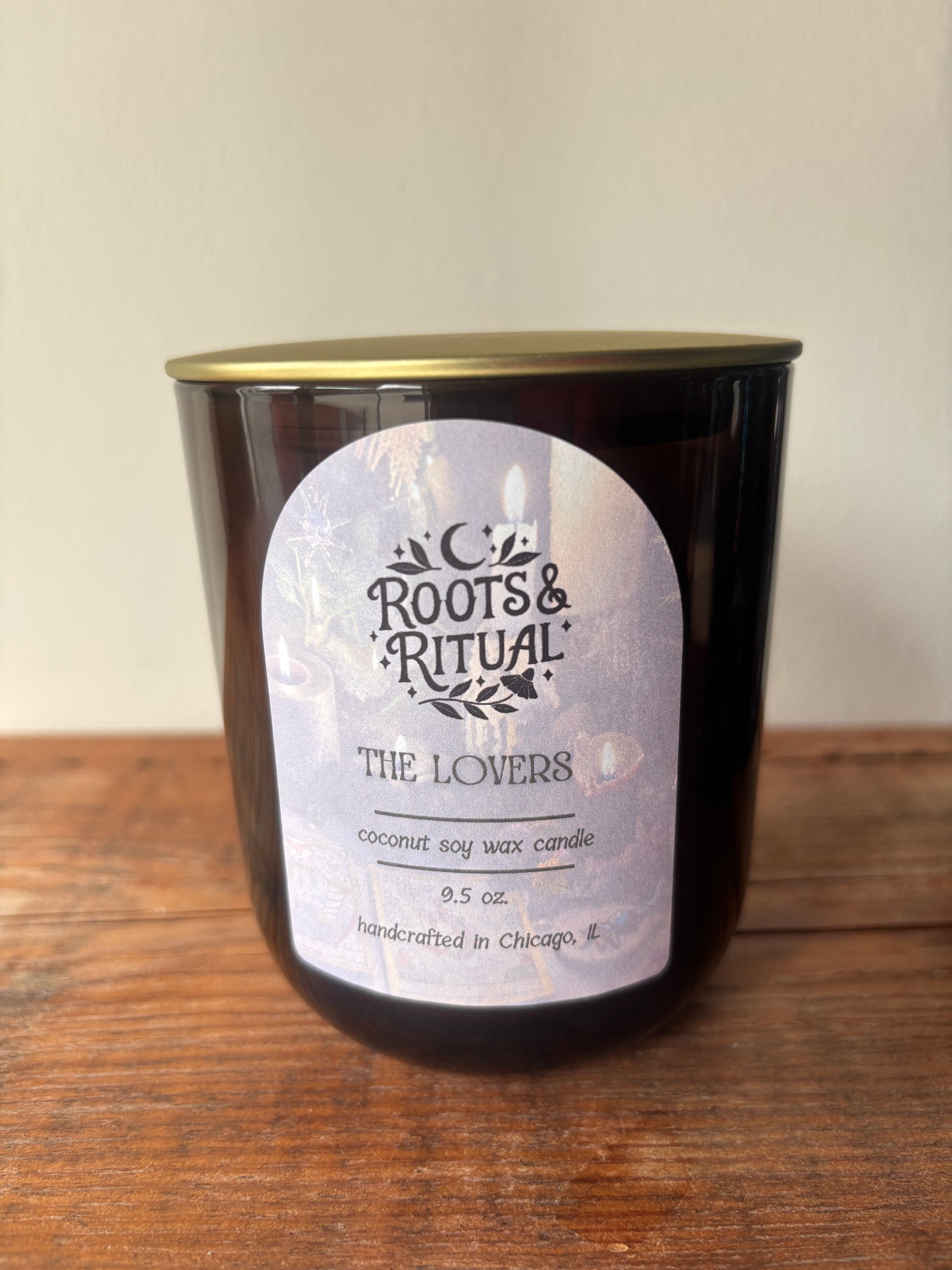 Candle in a black container with a label on a wooden surface