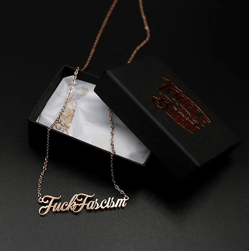 Gold Fuck Fascism necklace on a black background