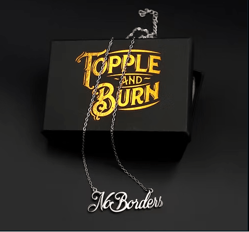 Necklace with 'No Borders' pendant on a black box with 'Topple and Burn' text.