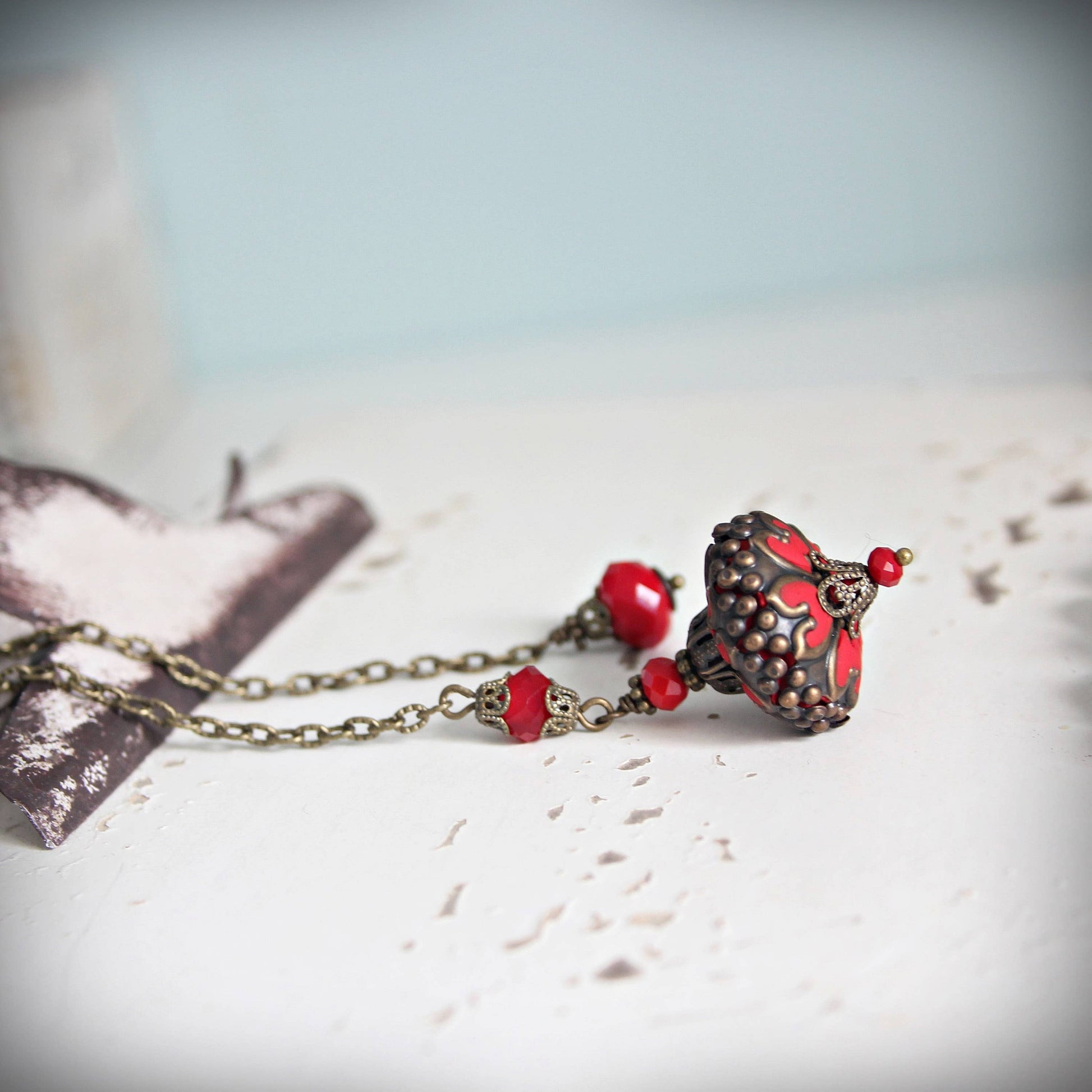 Necklace with red beads and a decorative clasp on a textured surface