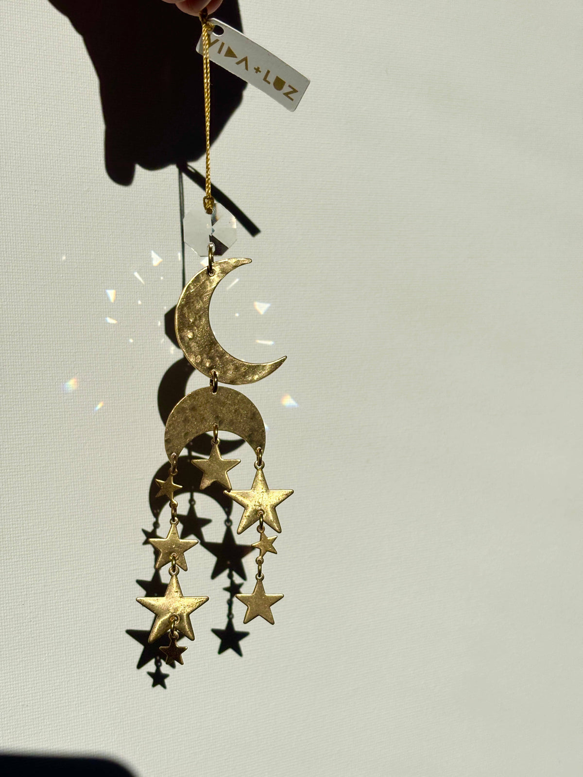 Decorative gold moon and star ornament on a plain background