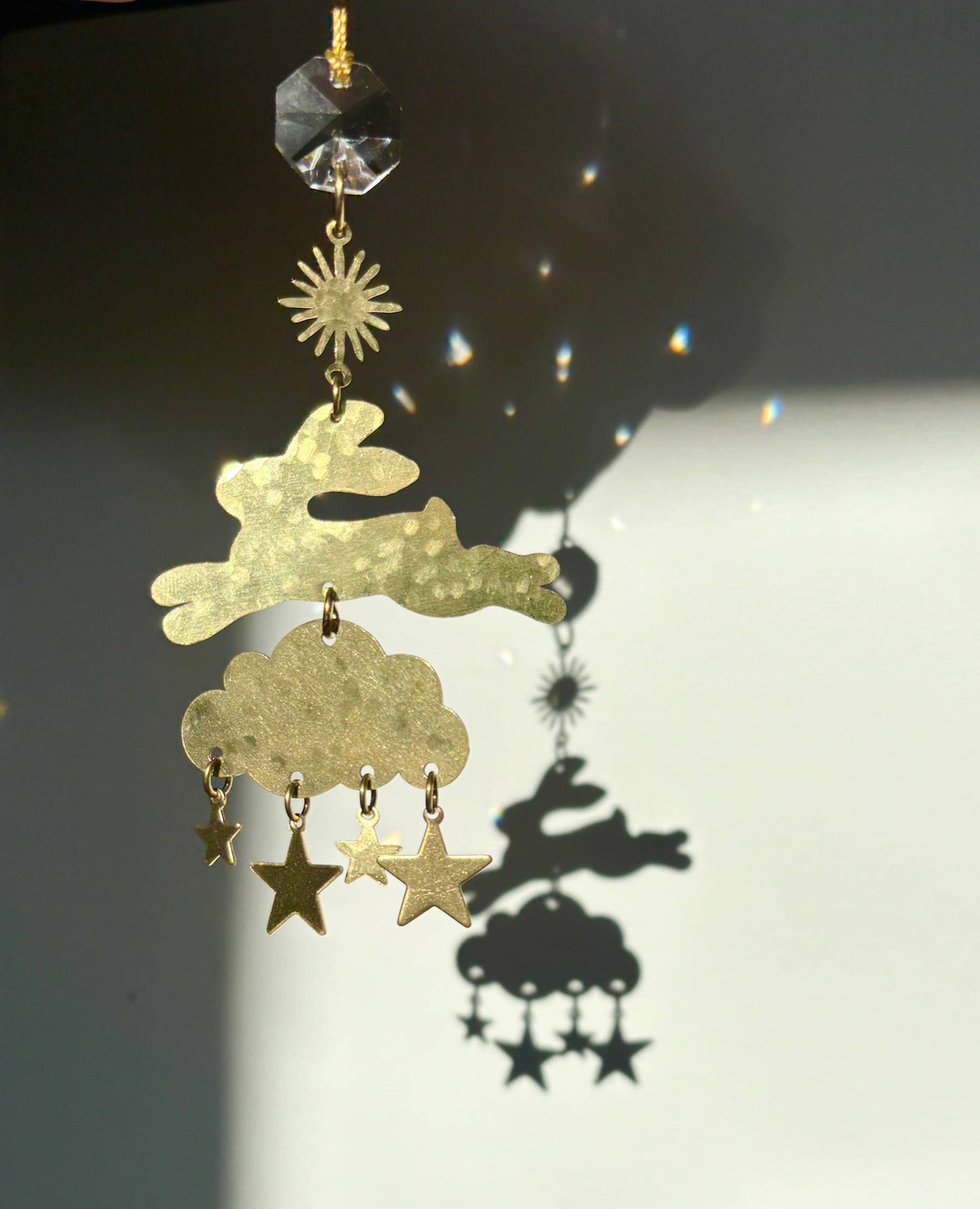 Decorative gold sun catcher with cloud, star, and sun design on a dark background