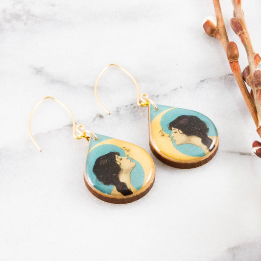 Teardrop-shaped earrings with artistic designs on a marble surface
