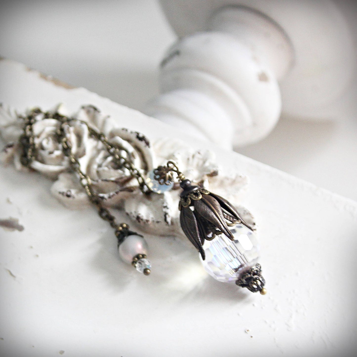 Vintage-style pendulum with floral and crystal elements on a white surface