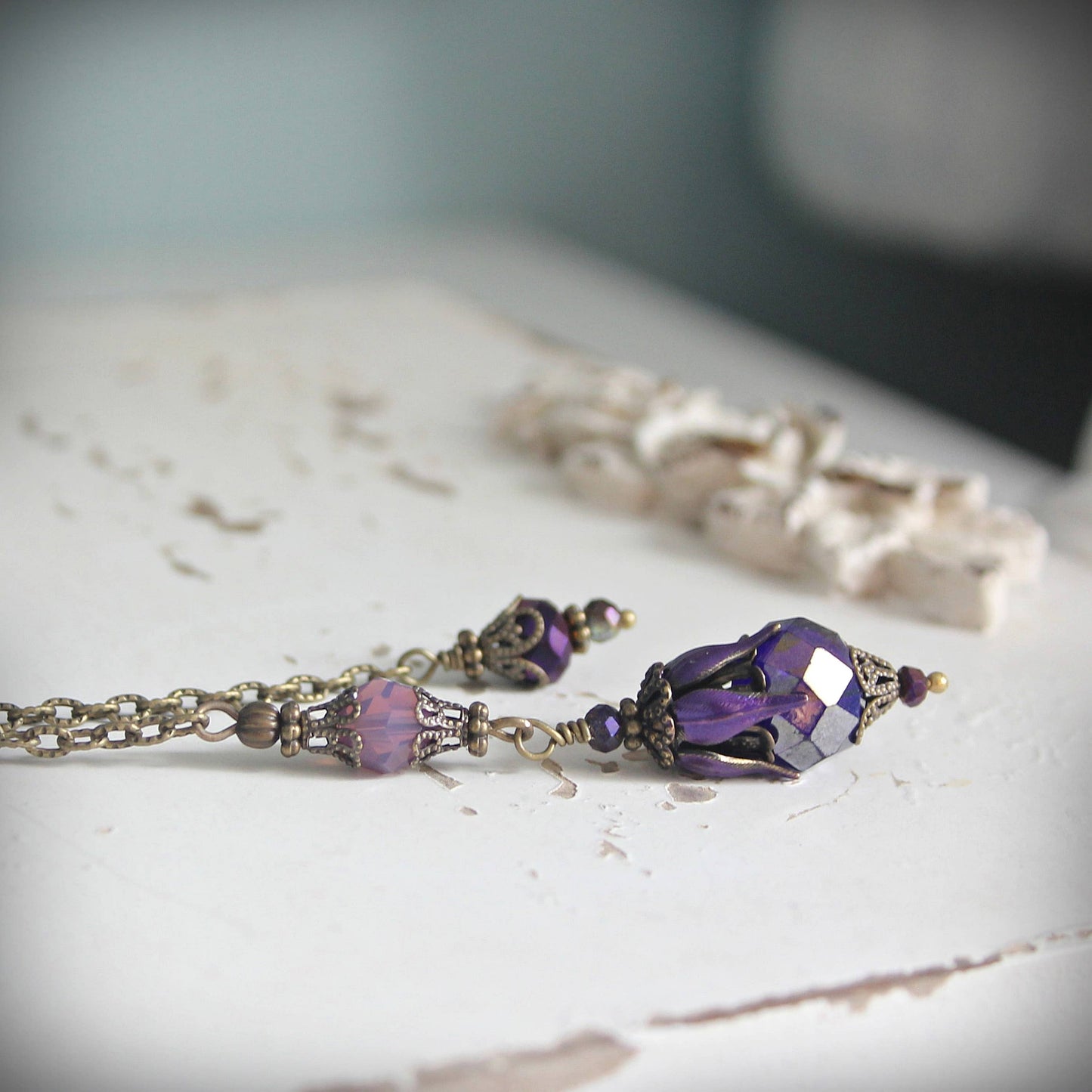 Purple beaded pendulum on a textured surface with a blurred background