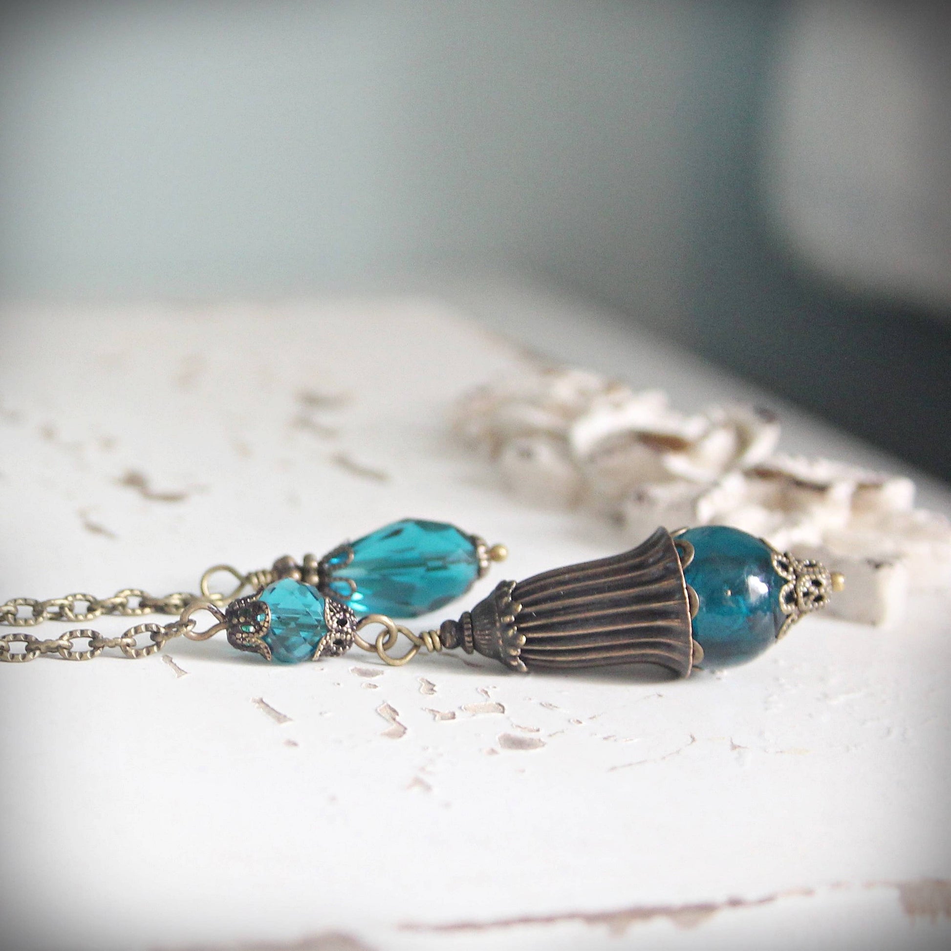 Pendulum with blue beads and a decorative clasp on a light surface