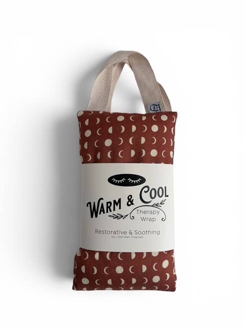 A fabric therapy wrap pouch with a brown and cream moon phase pattern, featuring a white paper label that reads 'WARM & COOL Therapy Wrap'.