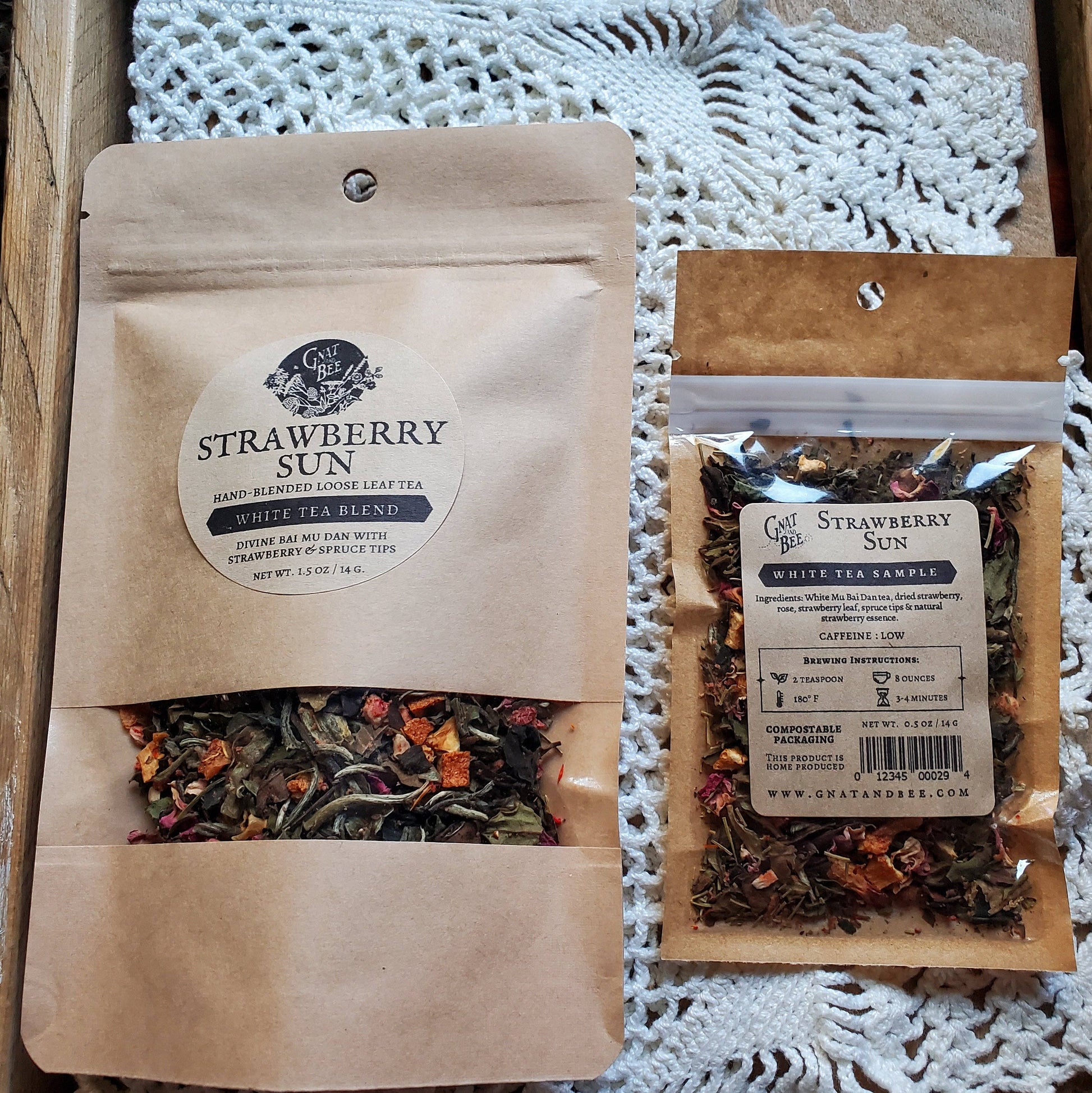 Two packages of Strawberry Sun white tea blend on a textured surface