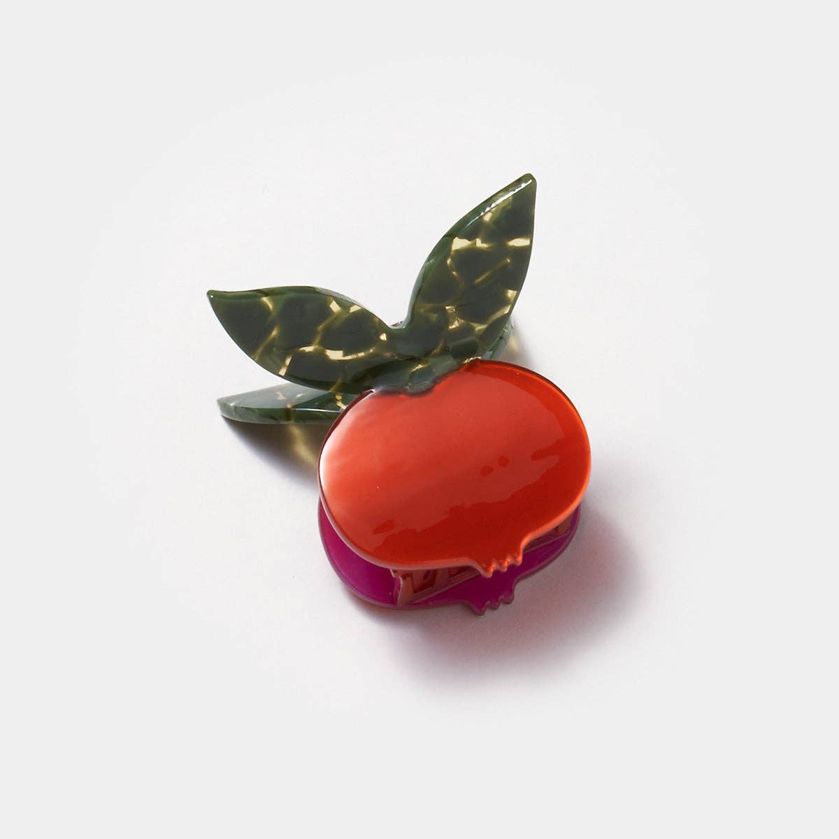 Decorative clip shaped like a pomegranate with green leaves on a white background