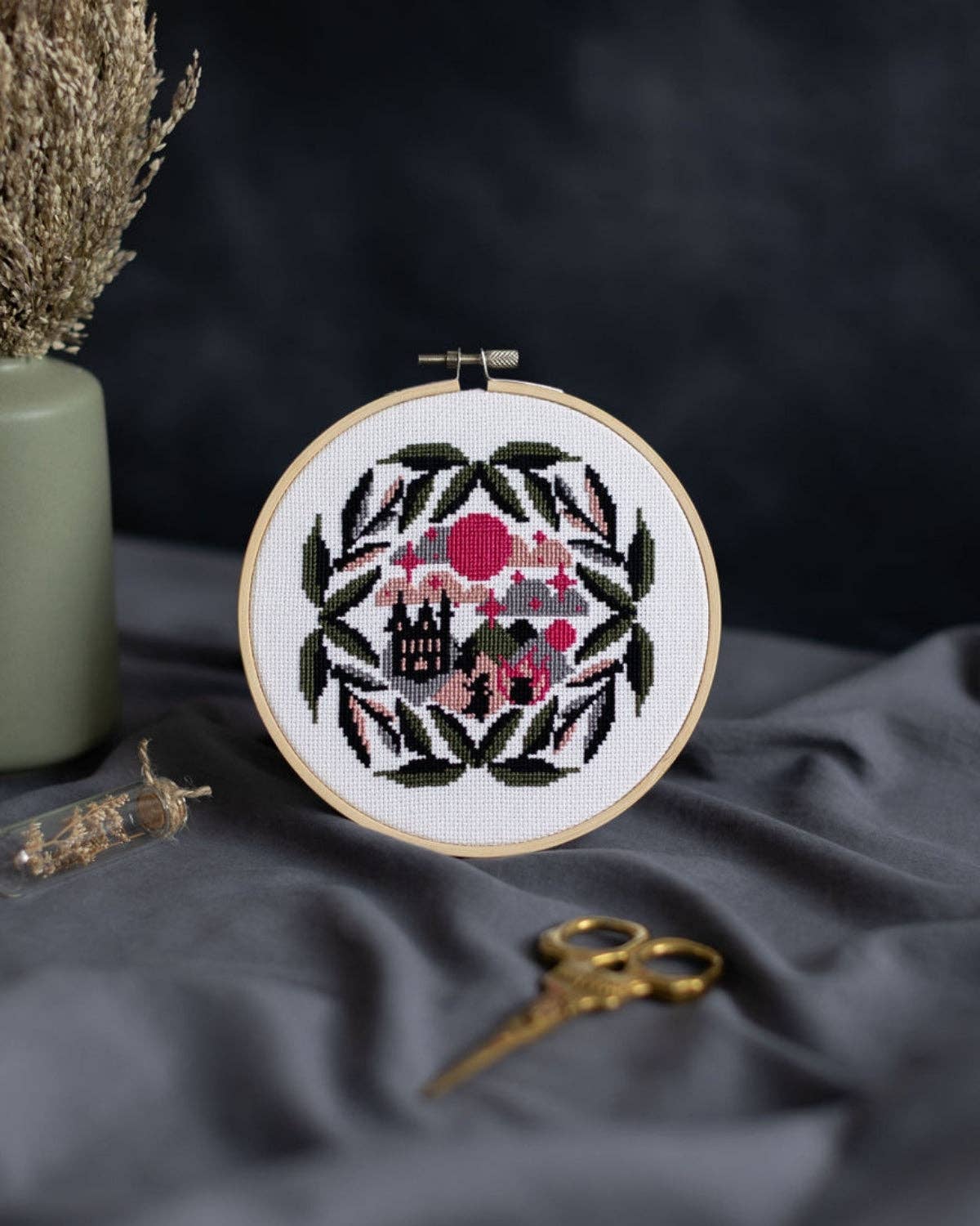 Cross-stitched embroidery hoop with floral design on a dark fabric background